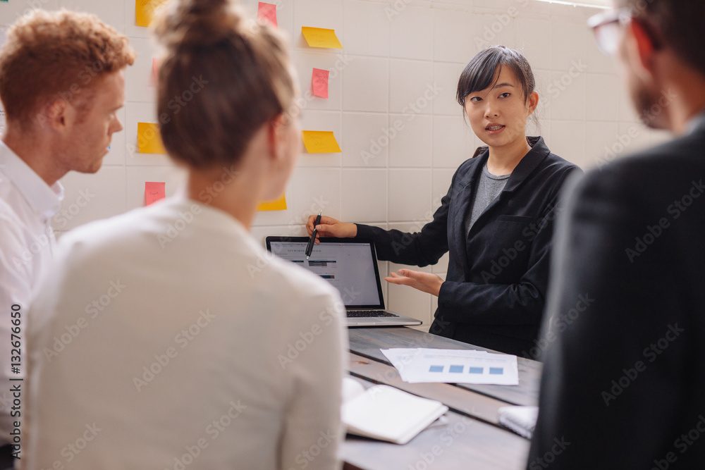 Group of business people discussing data on laptop at meeting