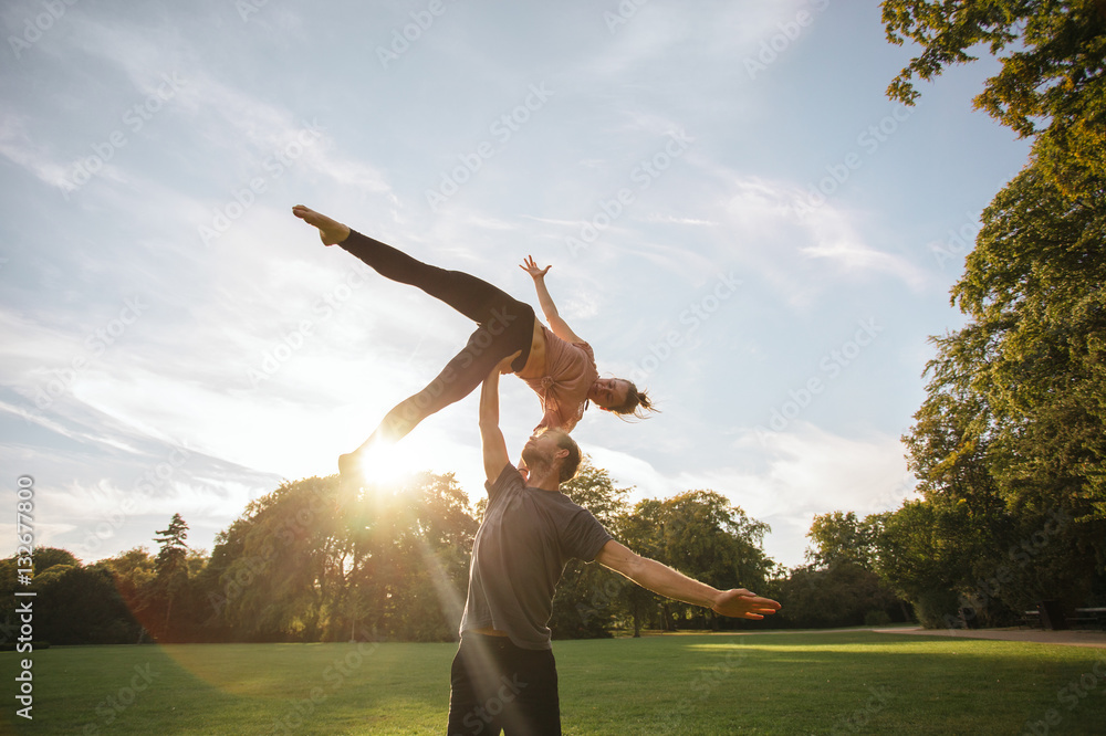 Young couple doing acroyoga at the park