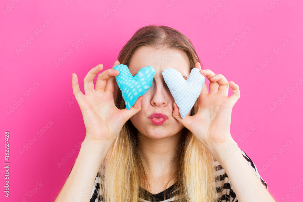 Happy young woman holding heart cushions