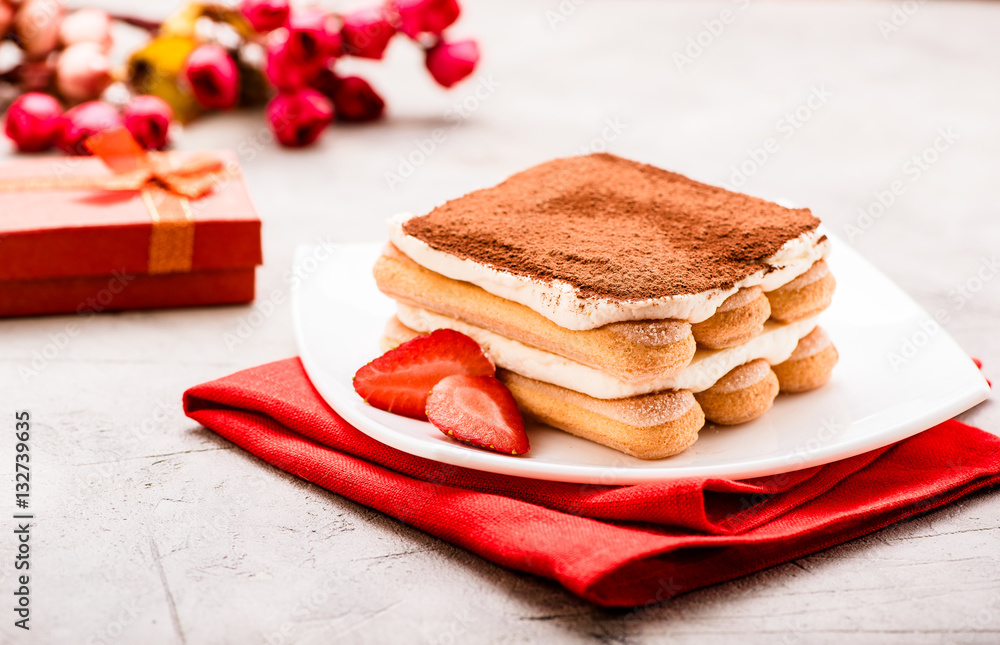 Tiramisu with strawberry and gift on the table. Valentines concept.