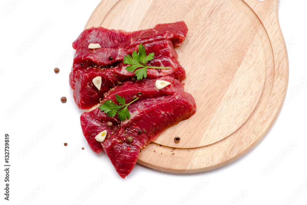 Pieces of meat with garlic and parsley on wooden board isolated. Raw beef. Top view.