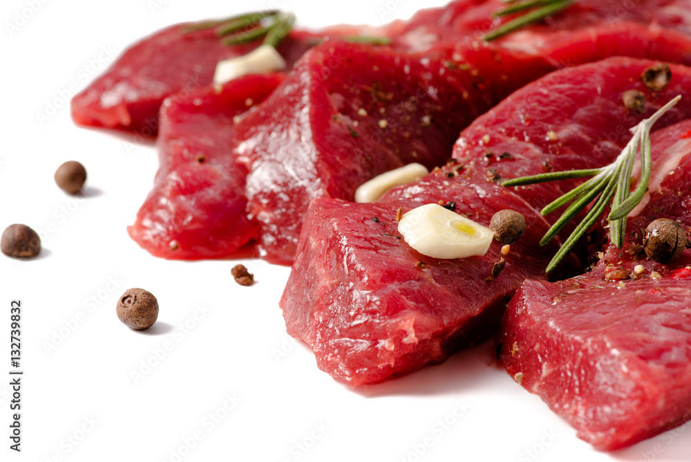 Pieces of meat with garlic and rosemary isolated on white background. Raw beef. Top view.