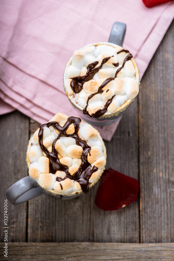 Smores drink. Two mugs of hot chocolate with marshmallows on a wooden table. Cocoa. Rose petals. Va