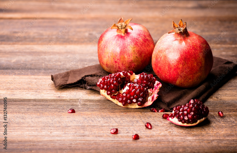 Pomegranate fruits with grains on wooden table.