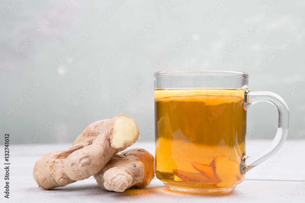 Ginger tea in a glass cup on wooden background