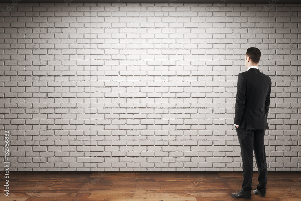 Man looking at empty brick wall