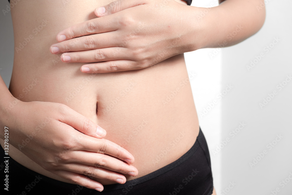 Pregnancy or diet concept, female hands protecting the stomach on white background.