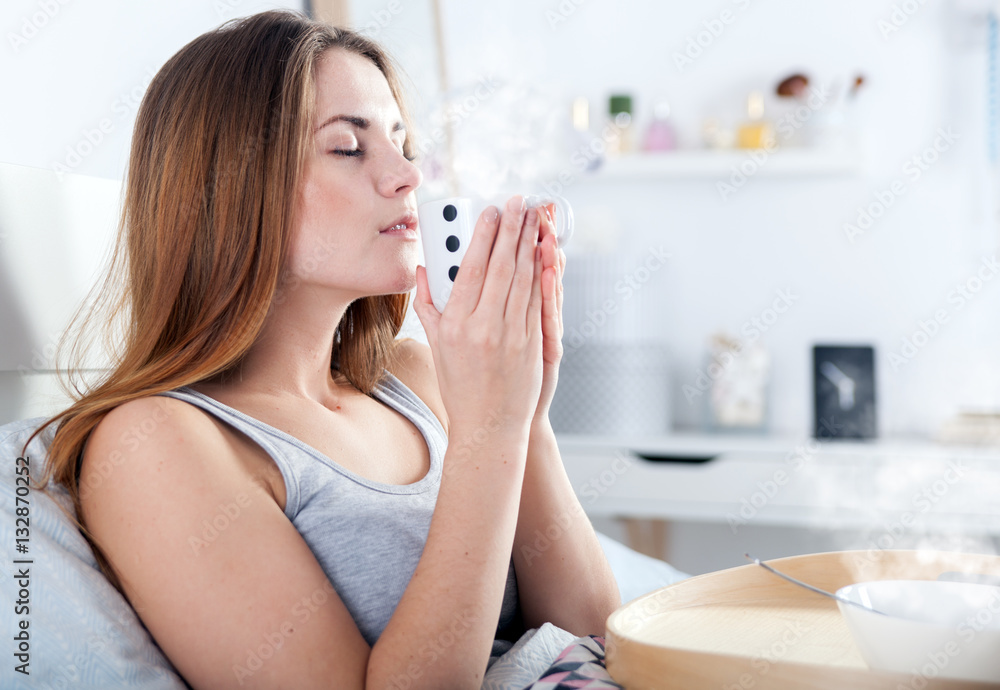 Morning at home, woman in bed drinking coffee