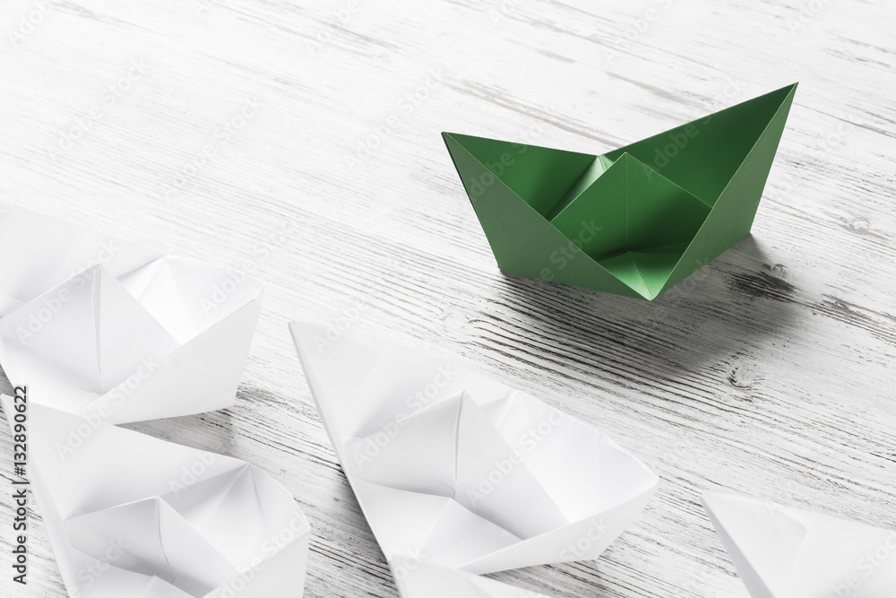 Business leadership concept with white and color paper boats on 