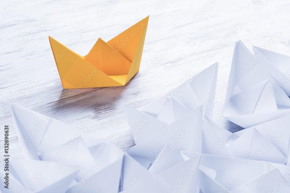 Business leadership concept with white and color paper boats on 