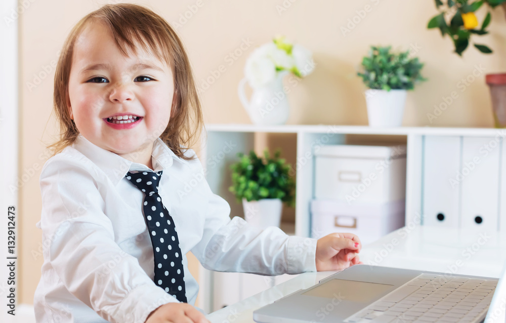 Happy toddler girl smiling while using a laptop