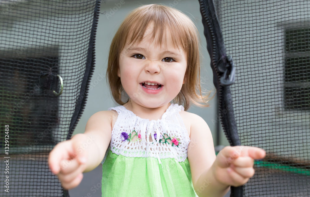 Toddler girl playing on her trampoline