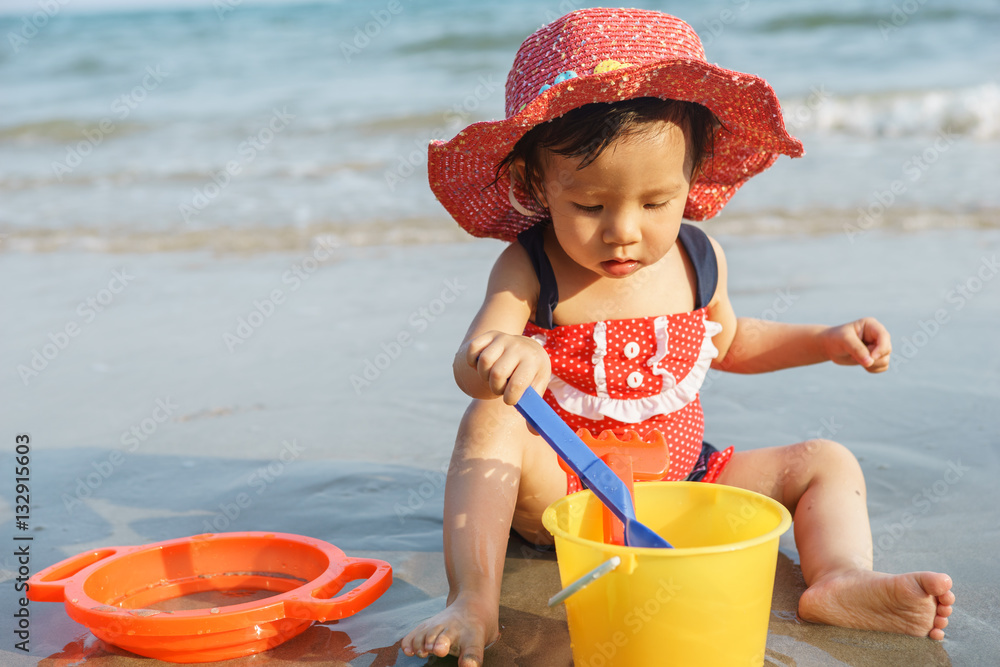 Small girl sitting on sand at beach