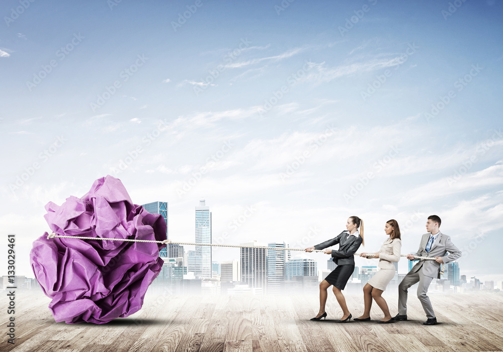 Young business people outdoors and huge paper ball as symbol of creativity