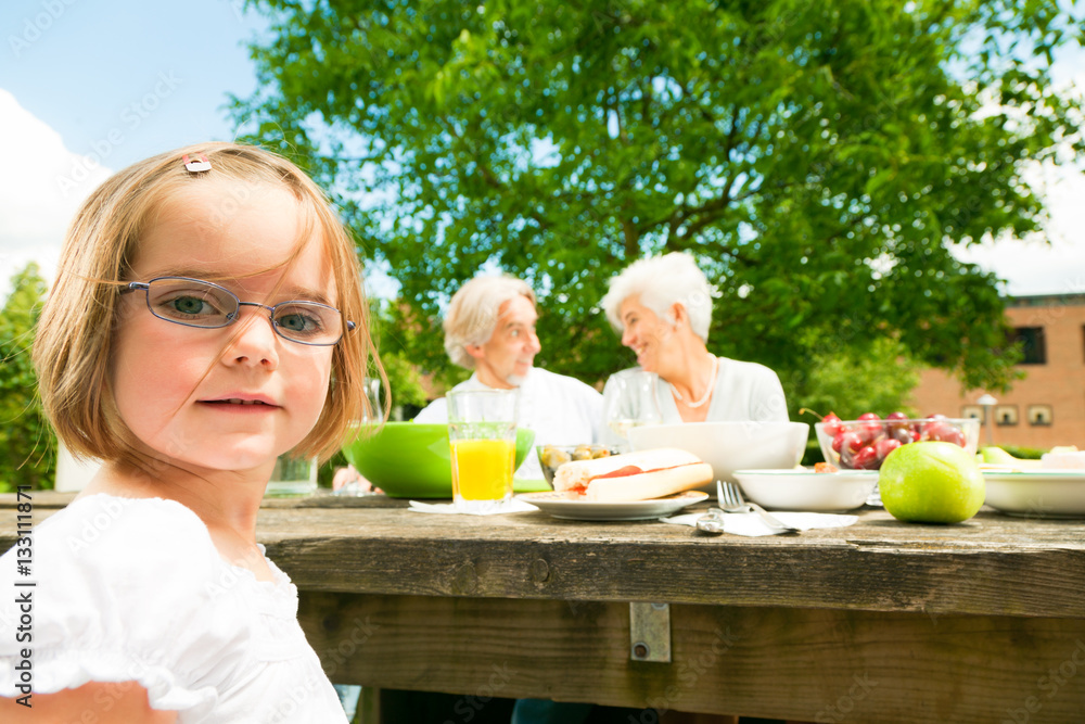 Little Girl And Her Grandparents Are Having A Picnic