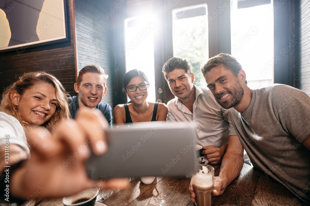 Diverse group of friends taking selfie at cafe