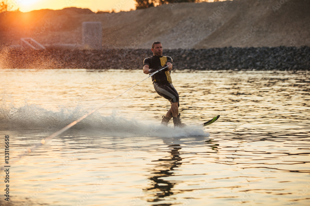 Man wakeboarding on lake at sunset