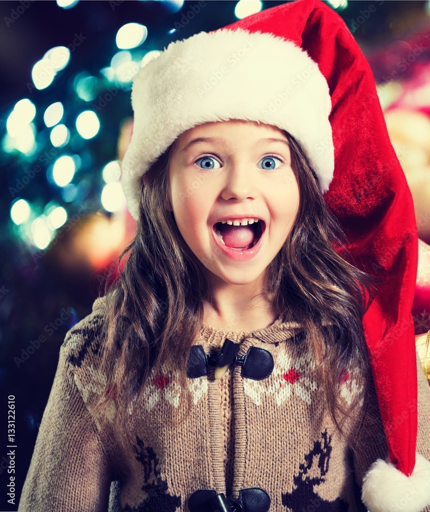 Happy child girl in a christmas hat.