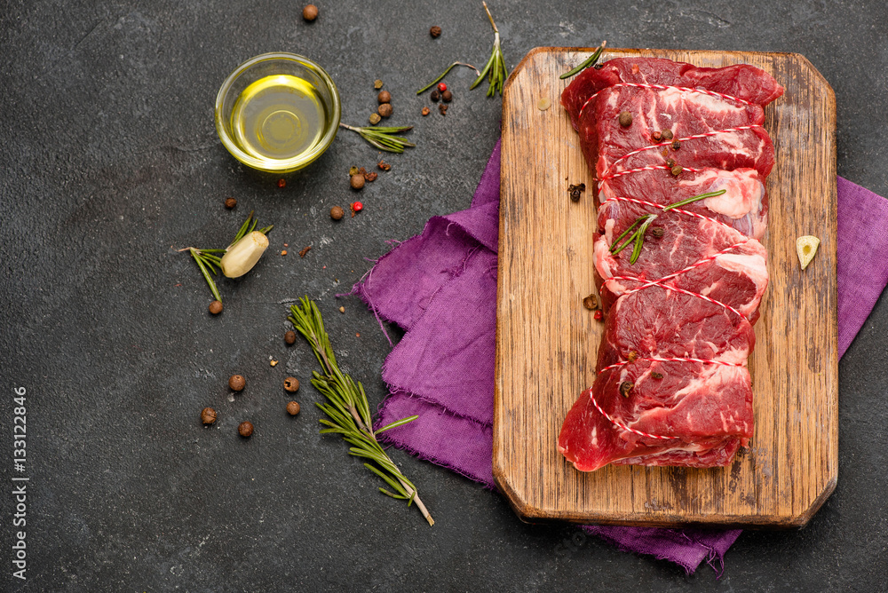 Raw meat with spices, olive oil and rosemary on wooden board. Fresh beef. Roast . Ready to roasting.