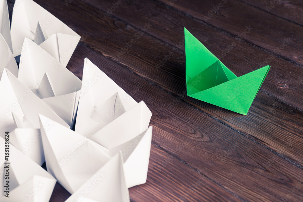 Business leadership concept with white and color paper boats on 