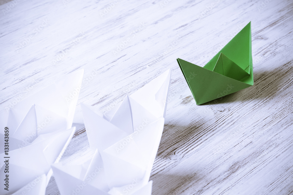 Business leadership concept with white and color paper boats on 