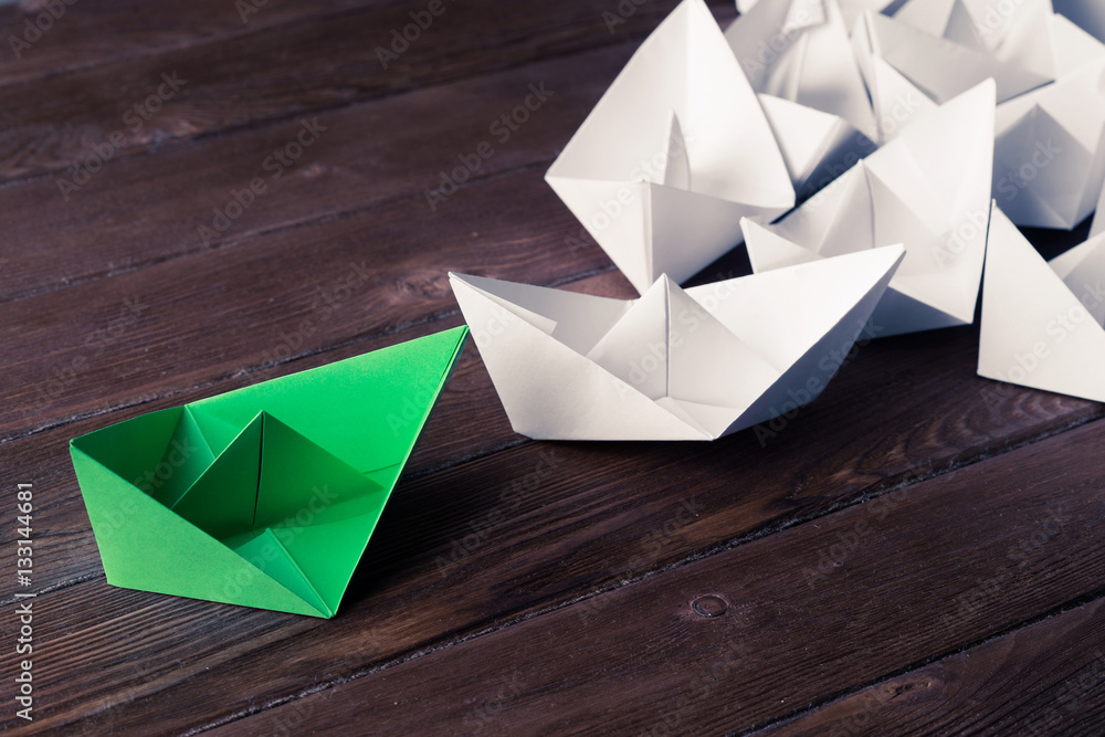 Business leadership concept with white and color paper boats on 