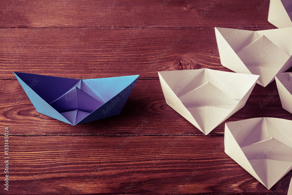 Business leadership concept with white and color paper boats on 