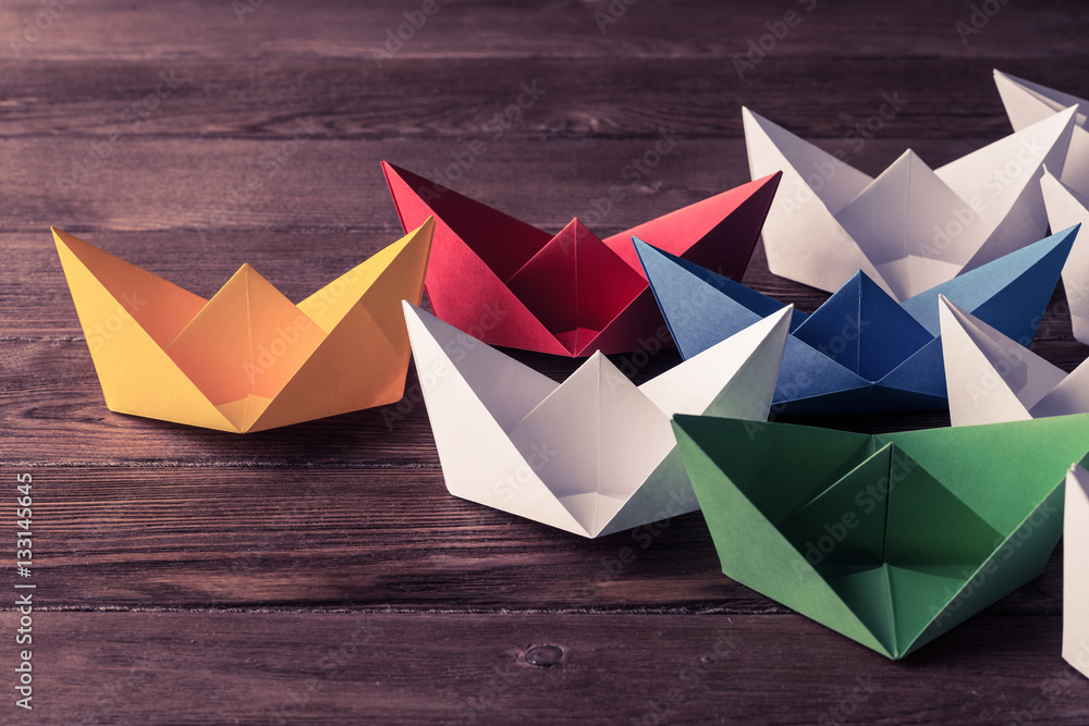 Business leadership concept with white and color paper boats on 