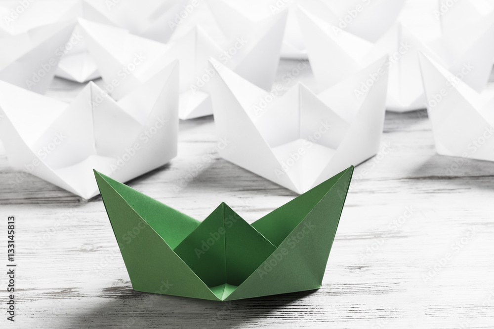 Business leadership concept with white and color paper boats on 