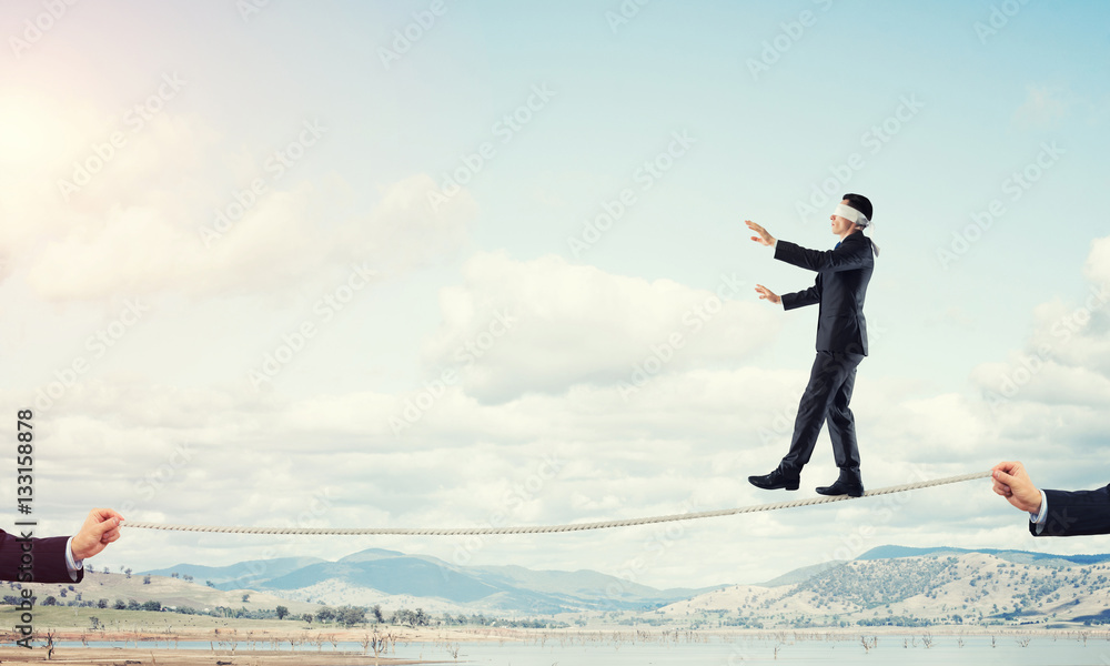 Business concept of risk support and assistance with man balancing on rope