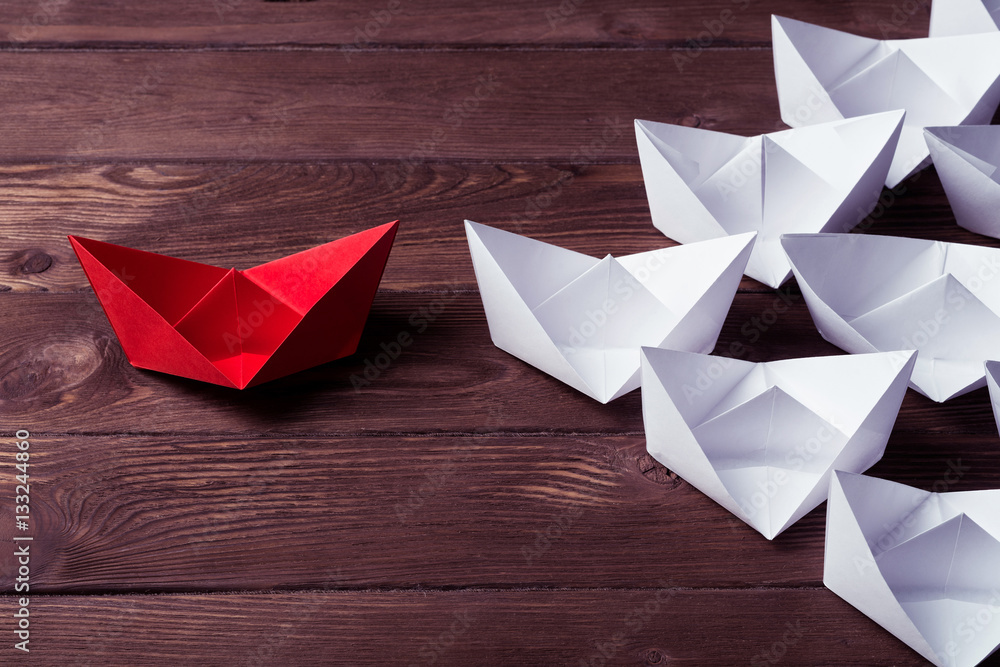 Business leadership concept with white and color paper boats on 