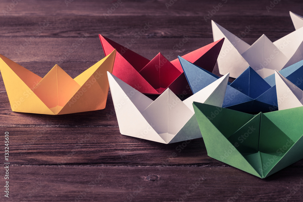 Business leadership concept with white and color paper boats on 