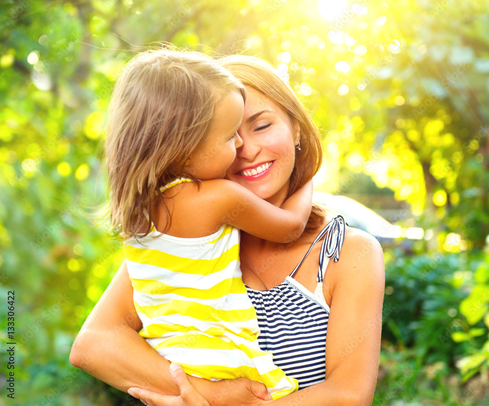 Beautiful mother and her little daughter playing in summer park together