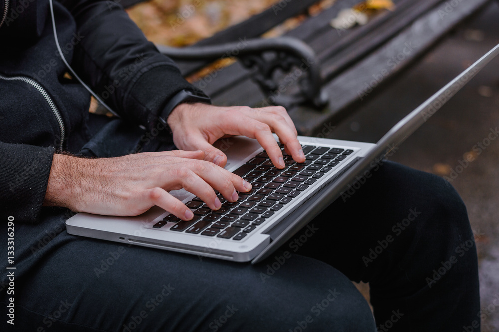 Closeup of a hands busy typing on a laptop in the park