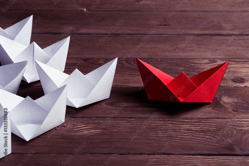 Business leadership concept with white and color paper boats on 