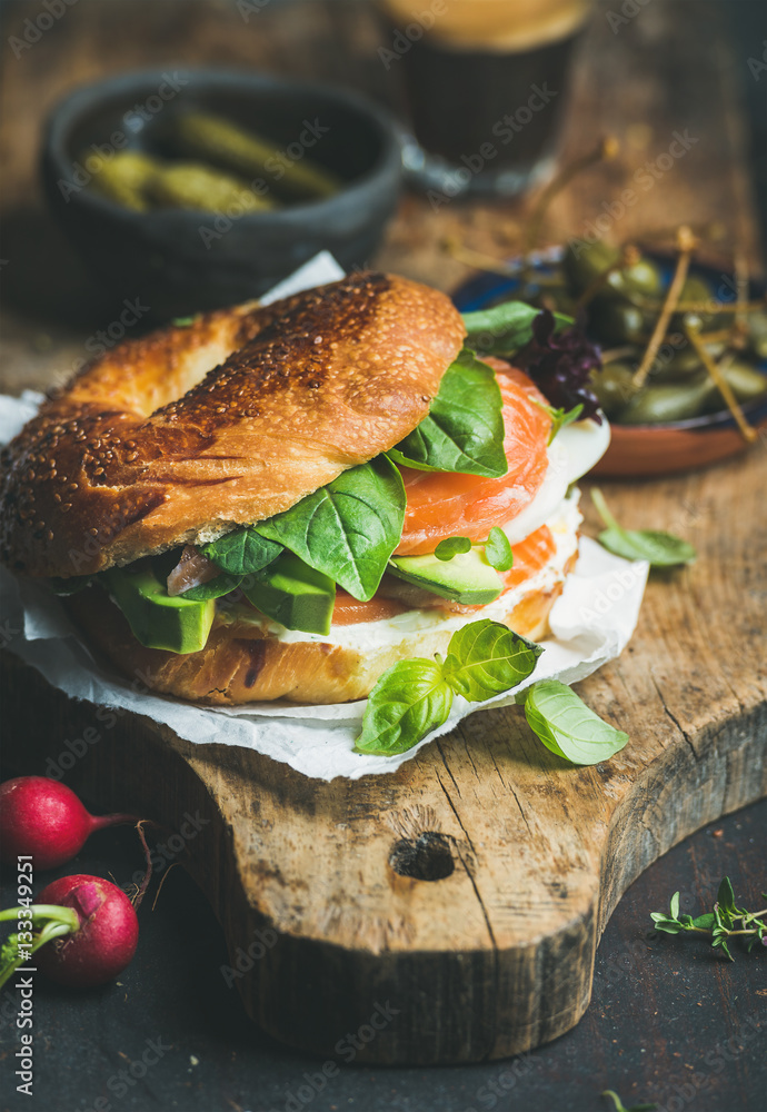 Breakfast with bagel with salmon, avocado, cream-cheese, basil and espresso coffee, rustic wooden bo