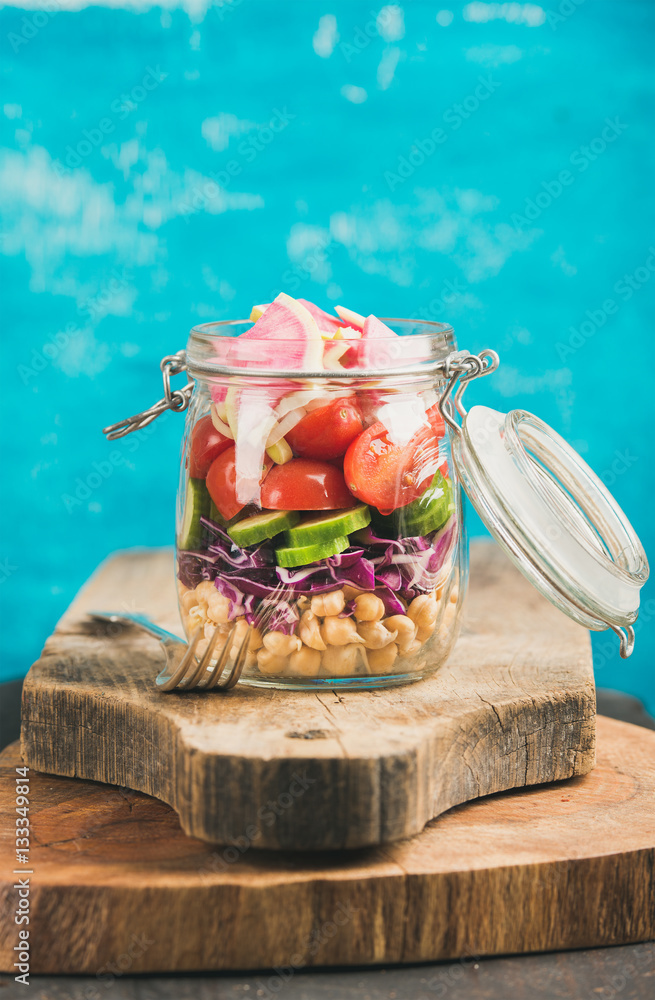 Healthy take-away lunch jar. Vegetable and chickpea sprout vegan salad in glass jar on wooden boards