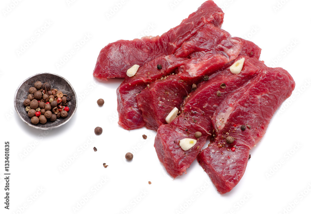 Pieces of meat with garlic isolated on white background. Raw beef. Top view.