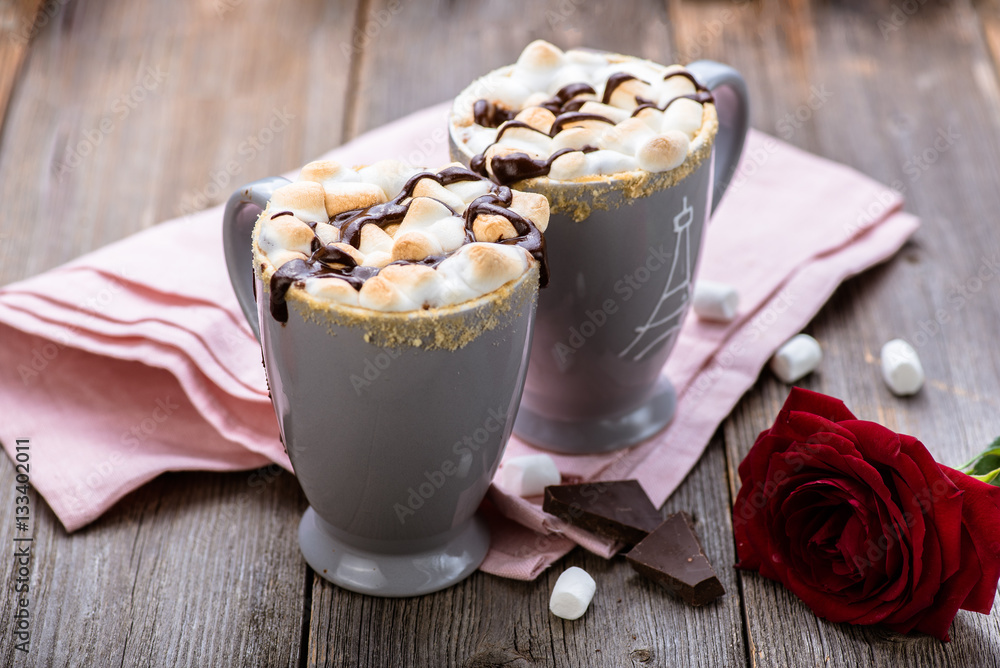 Smores drink. Two mugs of hot chocolate with marshmallows on a wooden table. Cocoa. Rose petals. Va