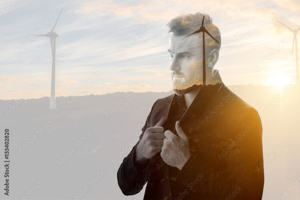 Double exposure portrait of a businessman thinking about renewable electricity combinated with sunse