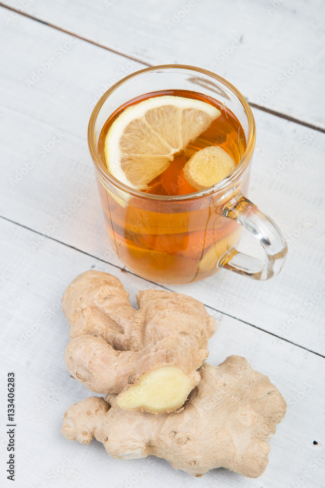 Ginger tea in a glass cup on wooden background