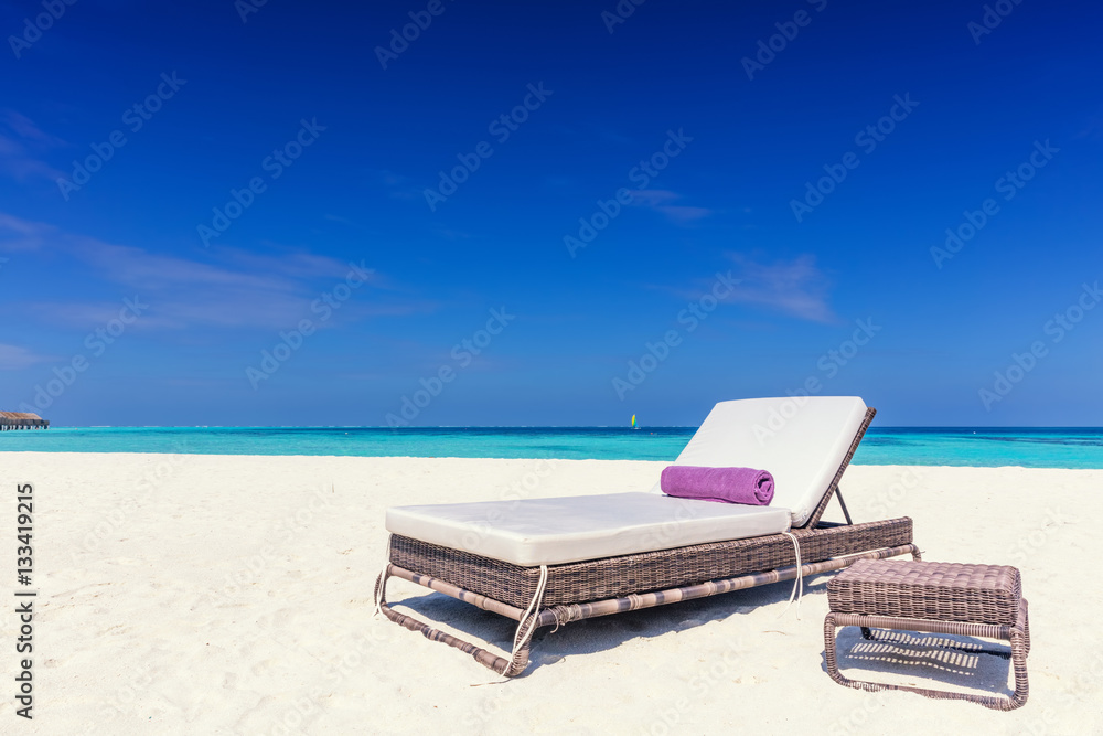 Deckchair on sandy tropical beacha a small island resort in Maldives, Indian Ocean