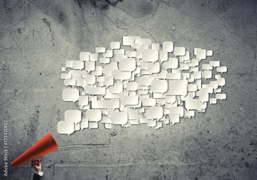 Hand of businesswoman holding red paper trumpet and speech cloud coming out