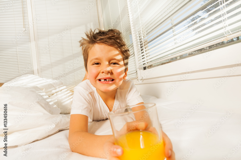 Happy boy with glass of juice in sunny morning