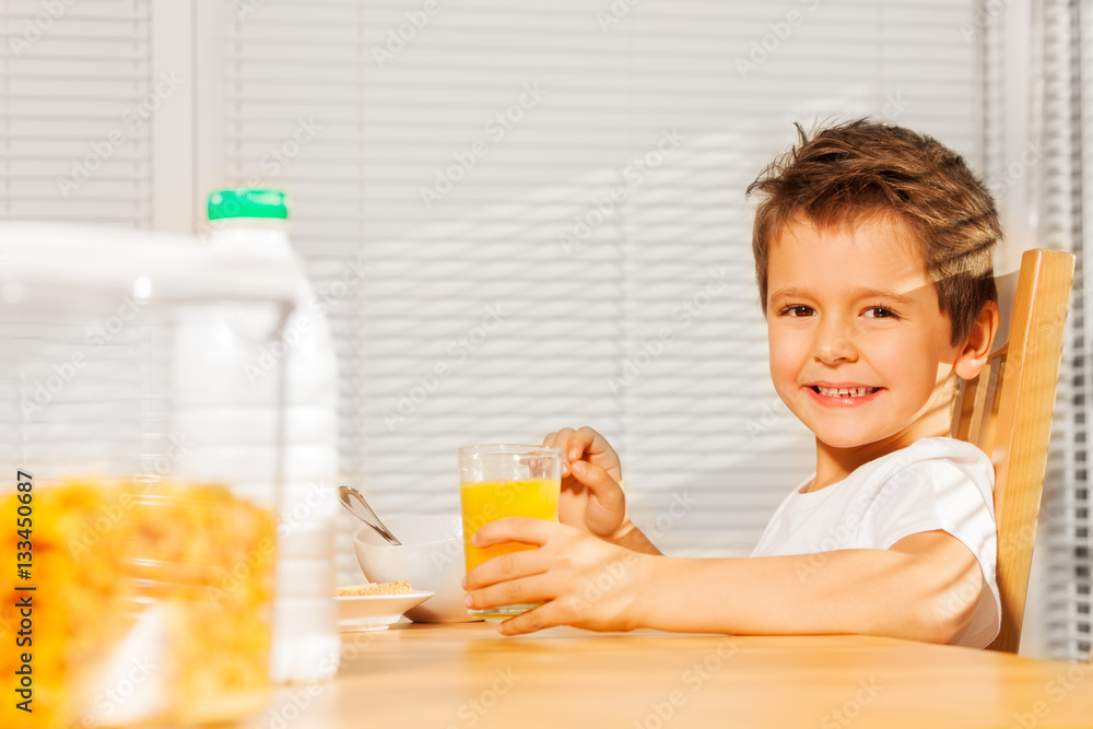 Happy boy drinking orange juice at breakfast