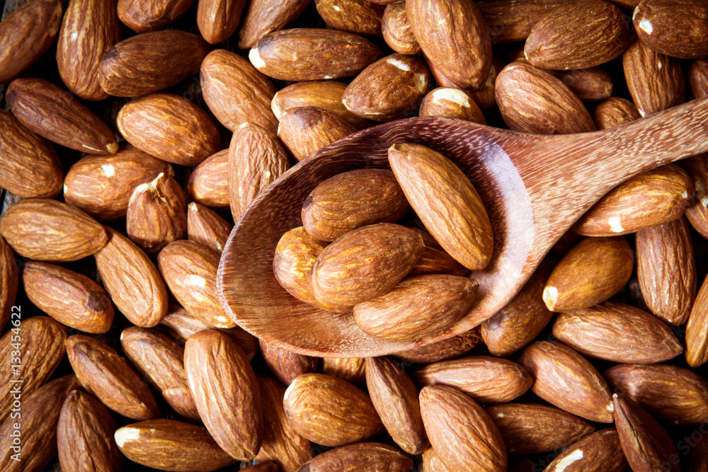 close up Peeled almonds nut in spoon on almond  background