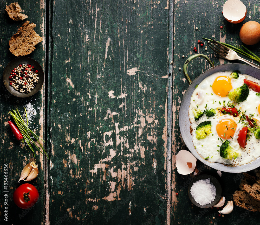 Pan of fried eggs, broccoli and cherry-tomatoes, top view