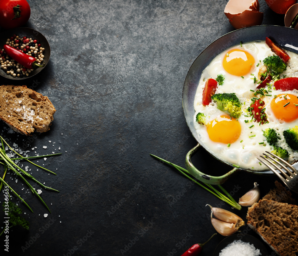 Pan of fried eggs, broccoli and cherry-tomatoes, top view