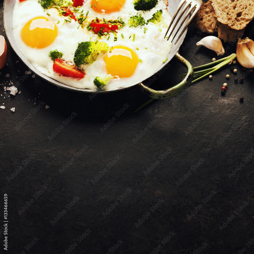 Pan of fried eggs, broccoli and cherry-tomatoes, top view