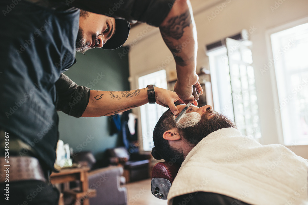 Professional barber shaving customer